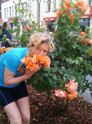 Foto 3: Radreise-Gartentraumtour, eine Frau riecht an einer Rose und lächelt